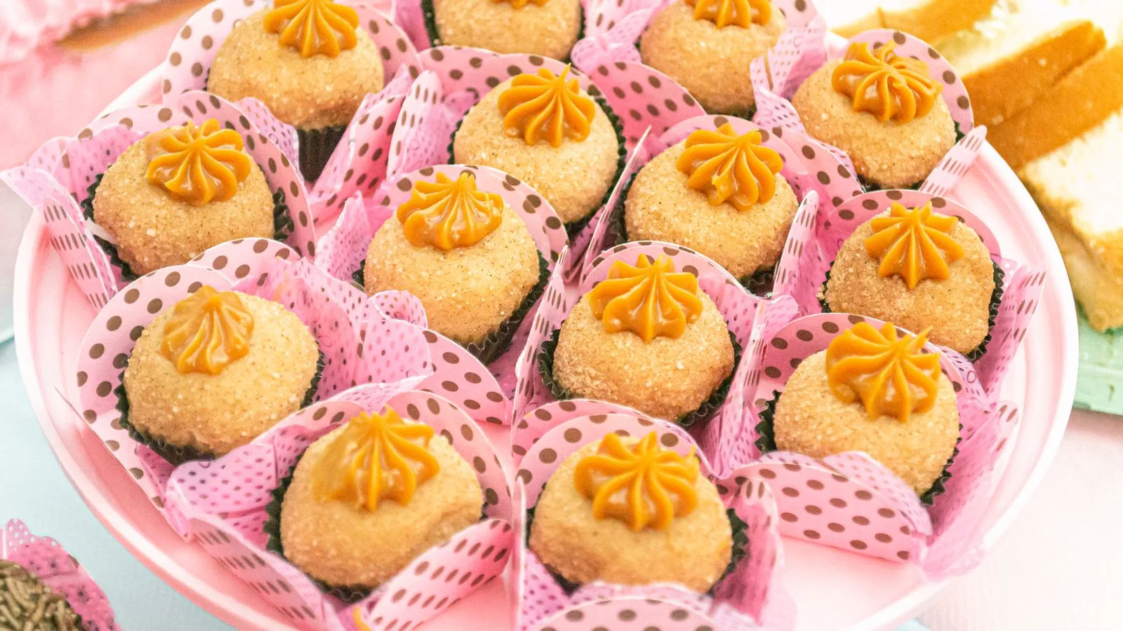 Assorted brigadeiros in pink polka-dot wrappers on a plate, ready to enjoy.