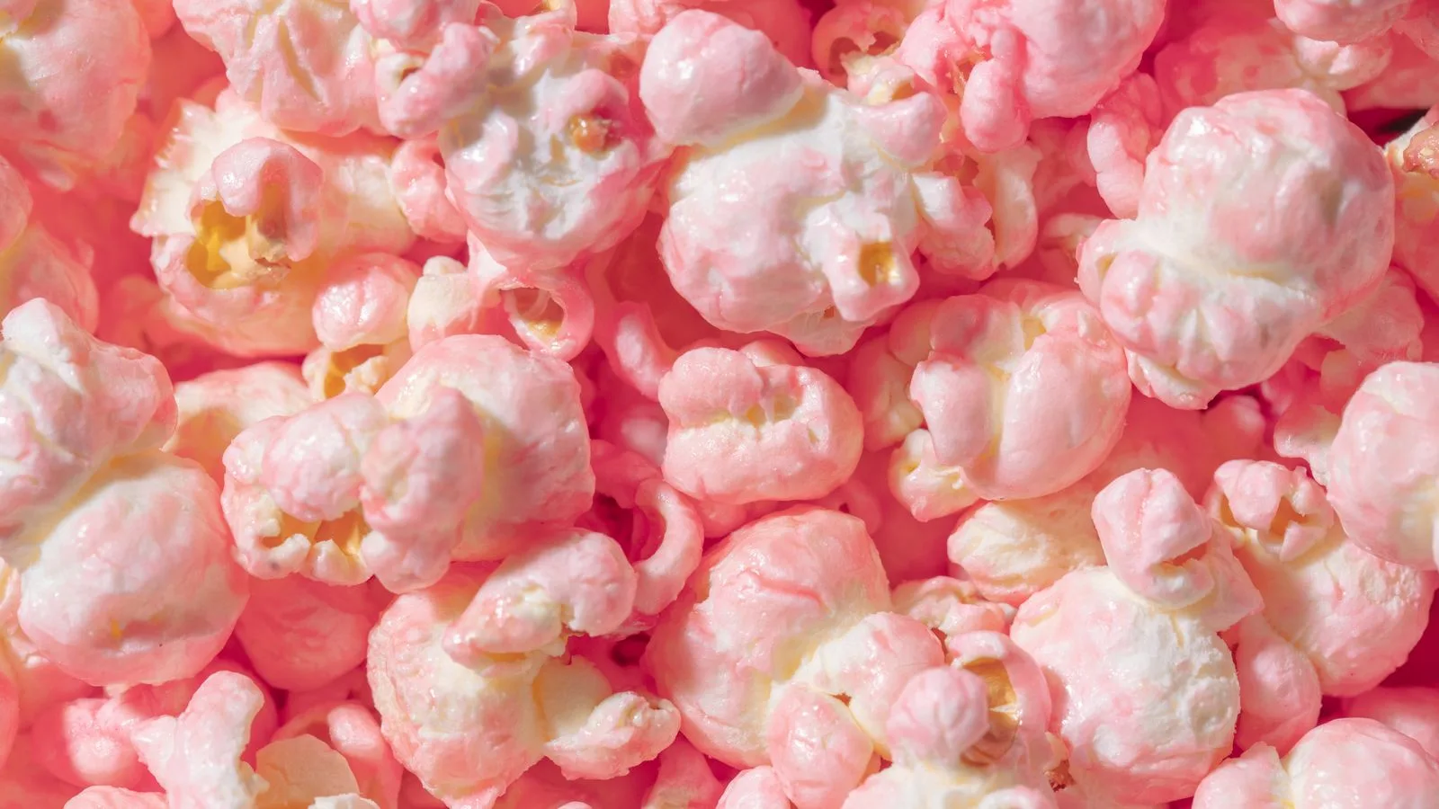 Vibrant close-up of pink candy coated popcorn, perfect for sweet snack themes.