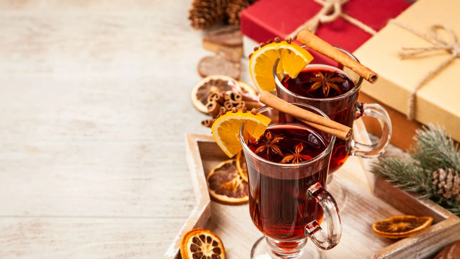 A cozy setup featuring mulled wine with cinnamon and orange slices, perfect for the holiday season.