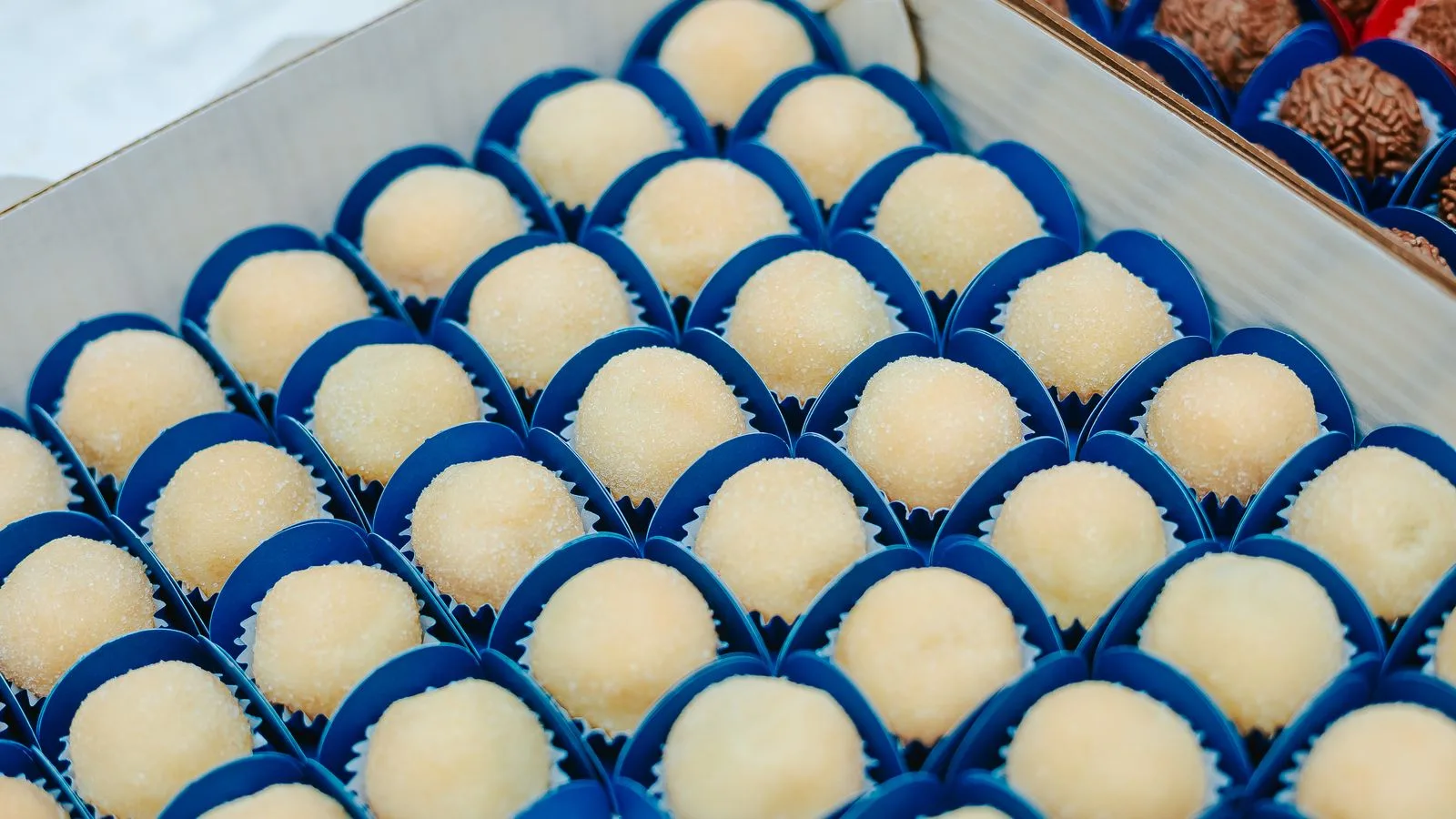 Assorted brigadeiros placed in blue wrappers, perfect for dessert displays.