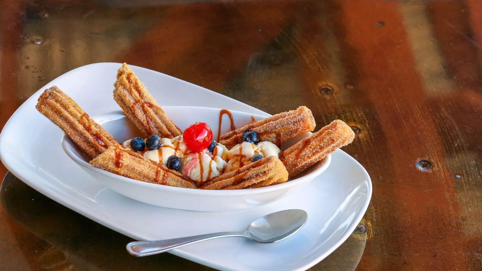 A tempting plate of churros served with ice cream, blueberries, and a cherry.