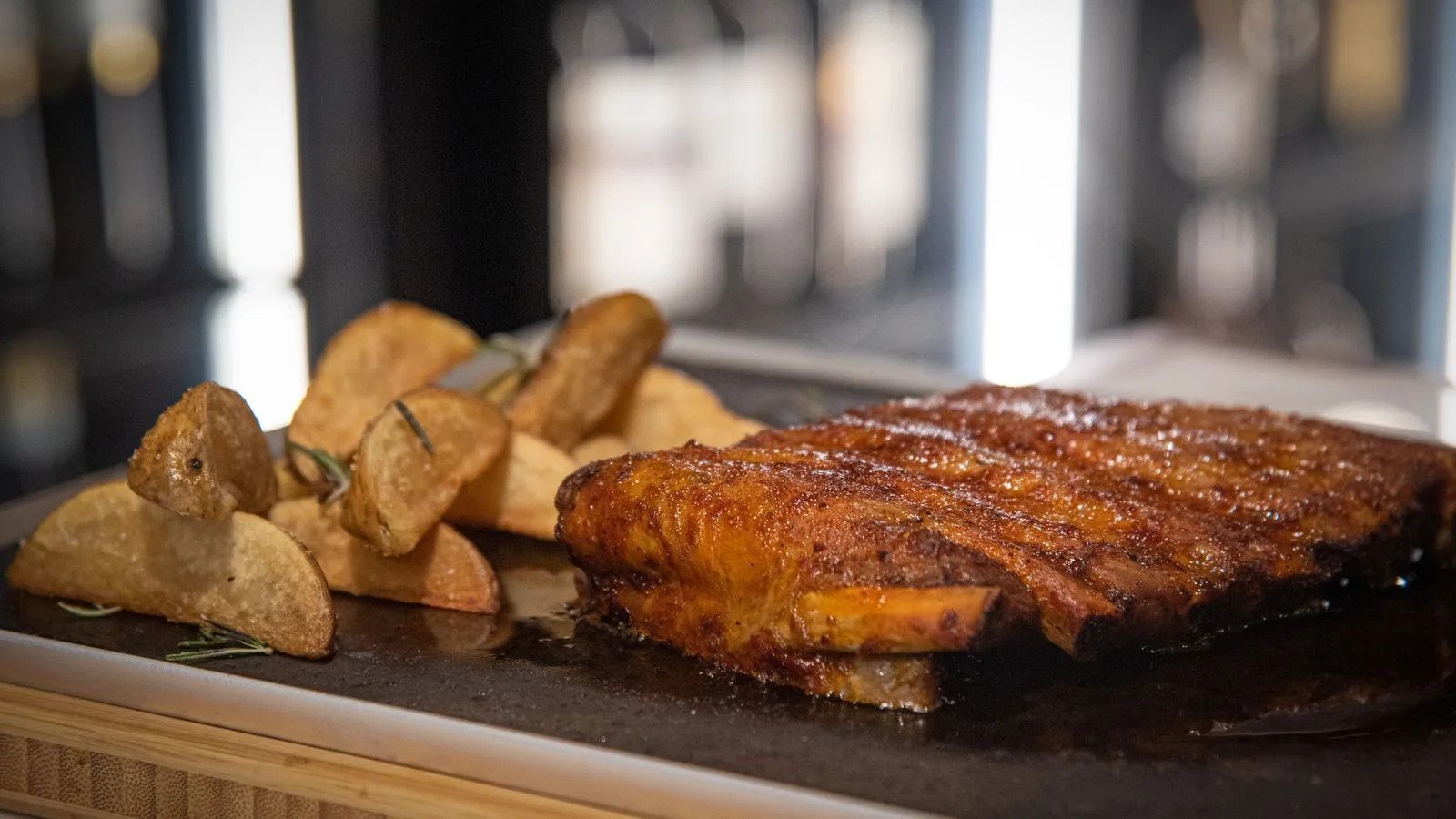 Deliciously crispy ribs served with rosemary roasted potatoes on a wooden board.