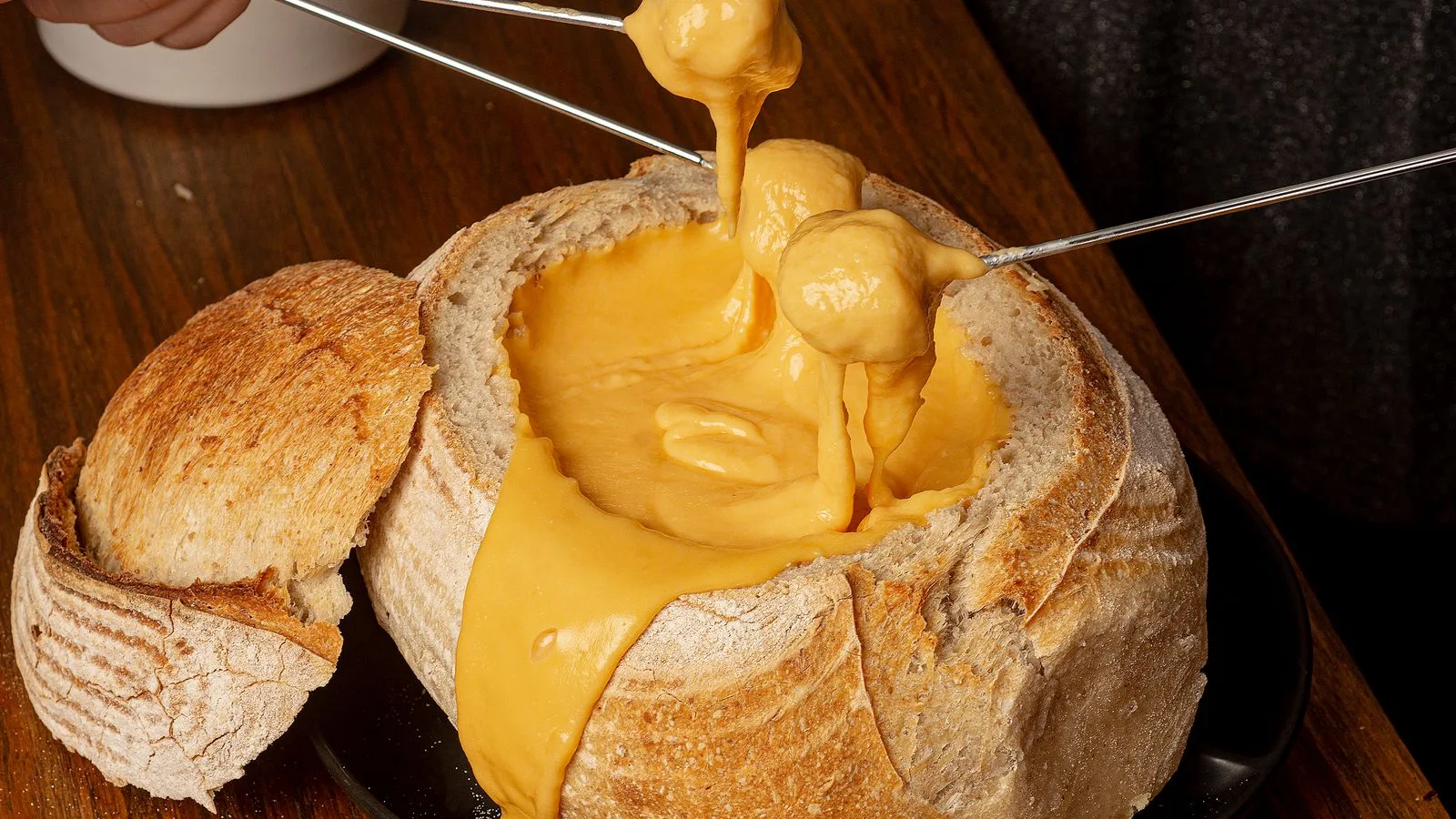 Scrumptious cheese fondue in a rustic bread bowl on a wooden table.