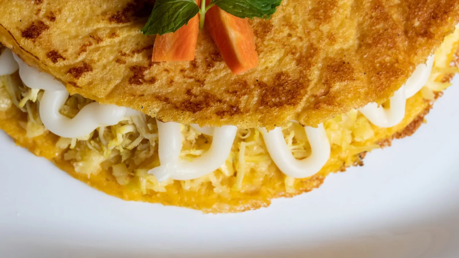 A delectable cheese-filled omelette garnished with fresh mint and carrot slices.