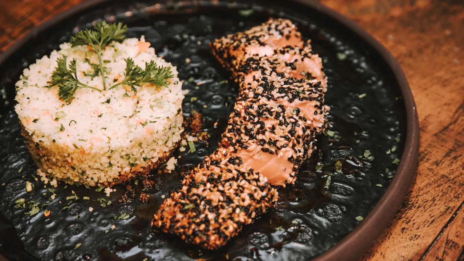 Tasty sesame-crusted salmon served with a flavorful rice medley on a rustic plate.