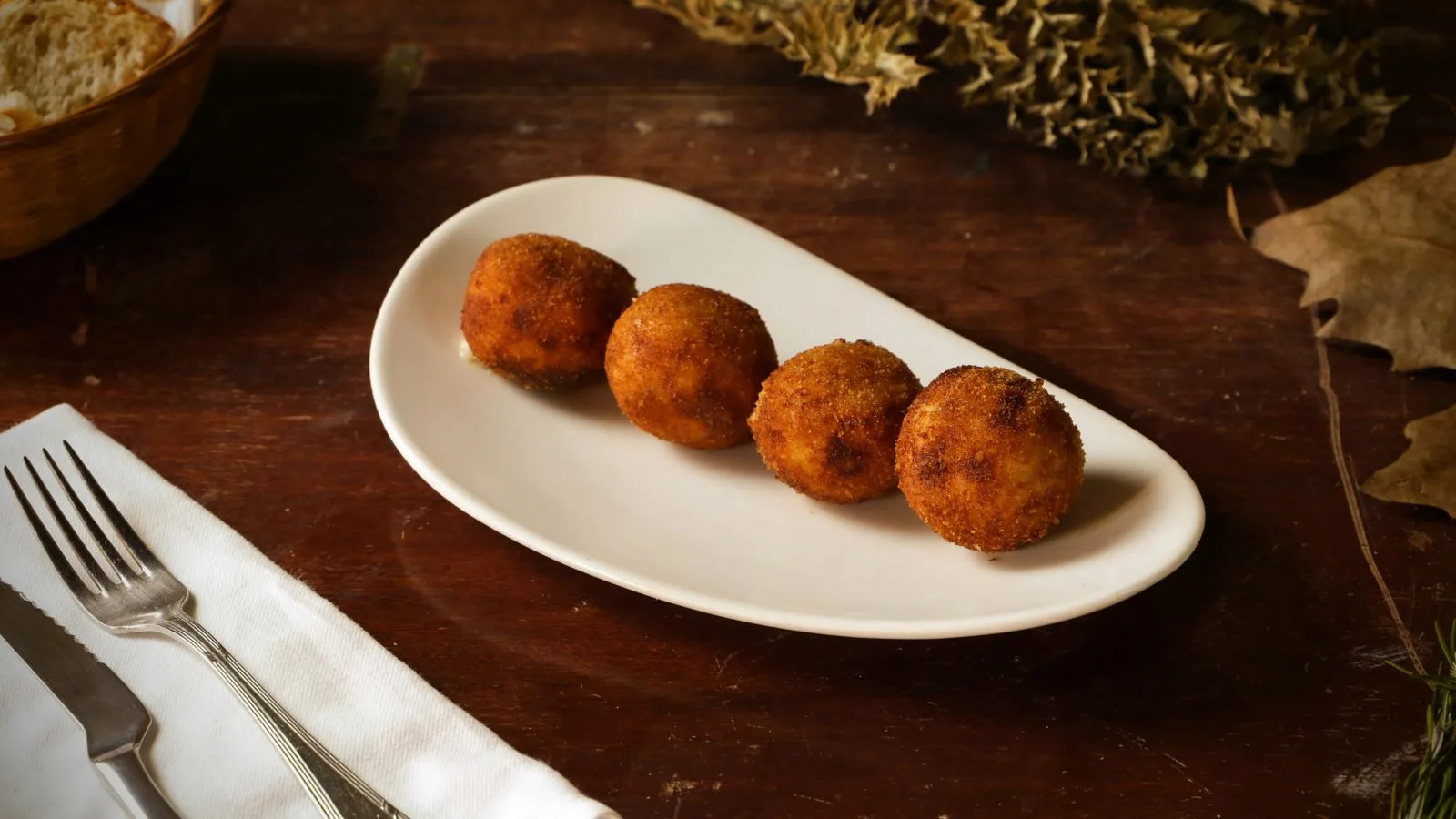 Appetizing fried arancini balls served on white plate in cozy setting.