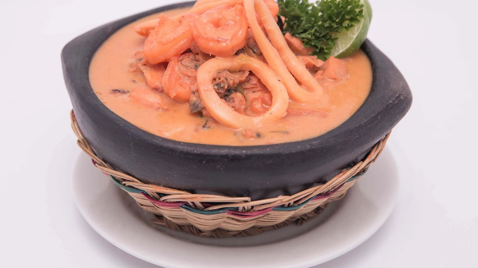 Close-up of a savory seafood stew, garnished with lime and parsley, served in a traditional bowl.