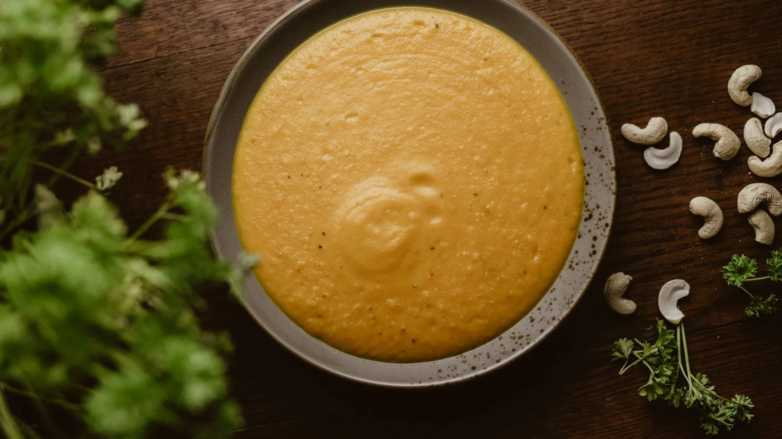 A warm plate of creamy cashew soup garnished with fresh herbs, perfect for a vegan meal.