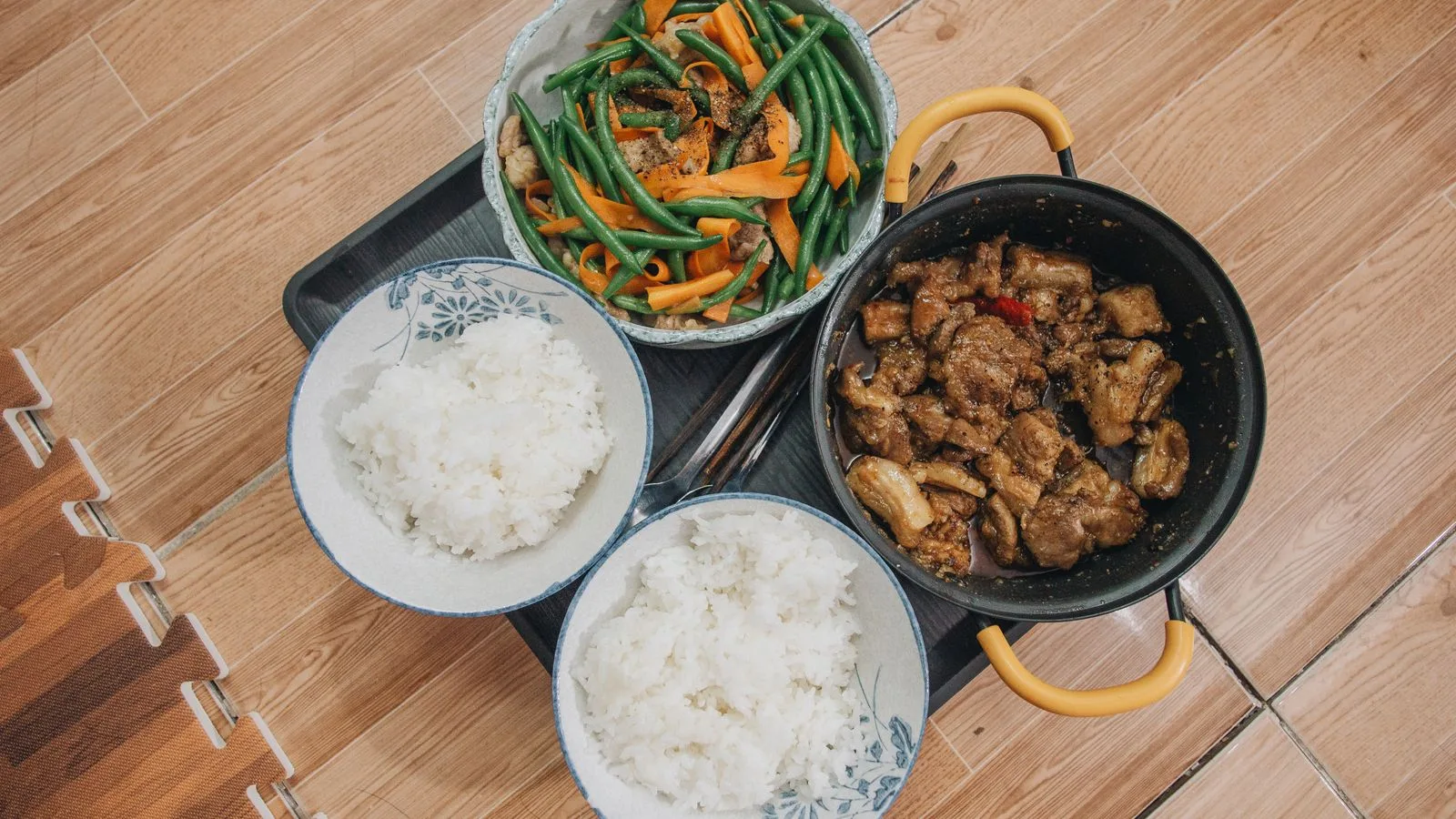 Close-up of a tasty Asian meal featuring pork, vegetables, and rice, beautifully arranged.