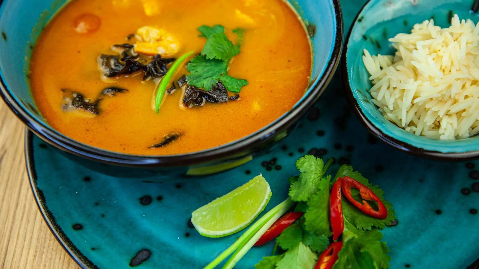 Thai curry with rice, lime, and chili on a turquoise plate, perfect for food lovers.