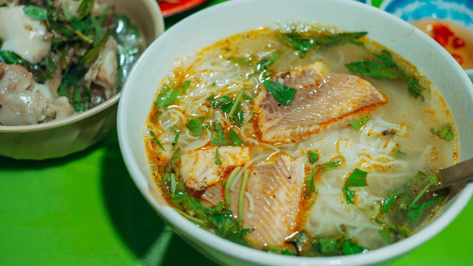 A vibrant bowl of Vietnamese fish noodle soup with herbs, showcasing authentic street food.