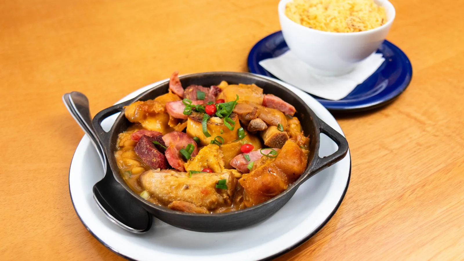 Delicious Brazilian feijoada served in a black pot with a side of rice.