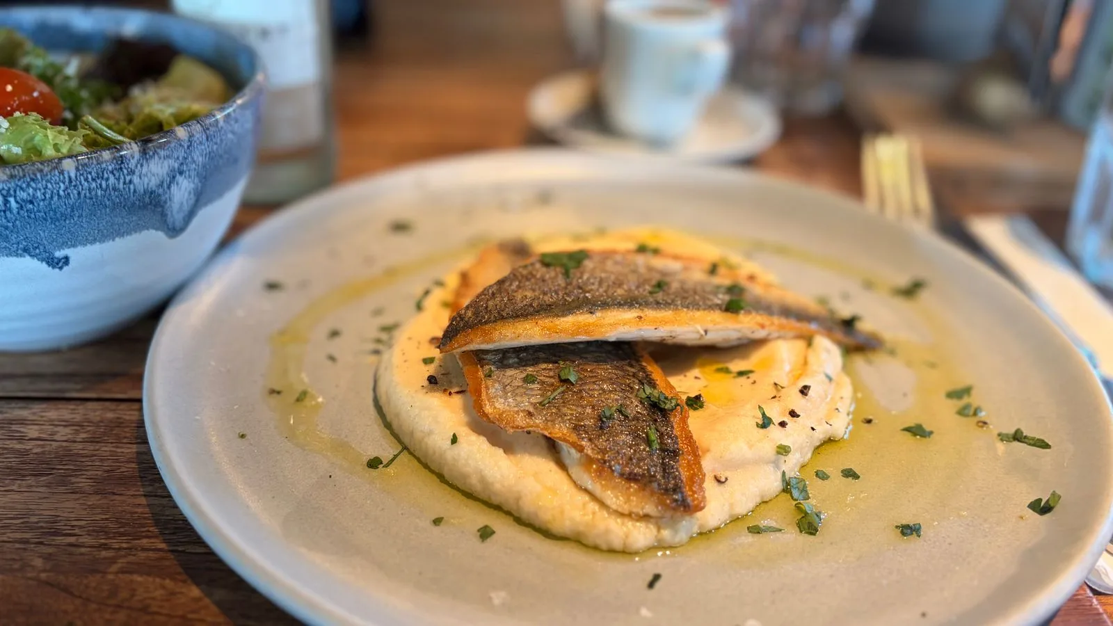 Tasty grilled sea bream served with polenta and a fresh salad, perfect for a healthy meal.