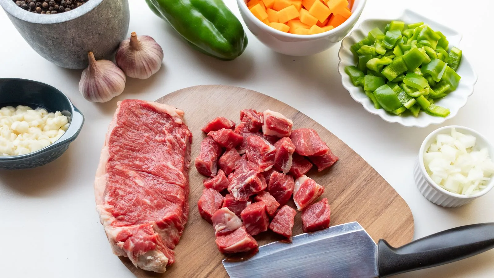 A variety of fresh ingredients including beef, vegetables, and seasonings ready for a homemade stew.