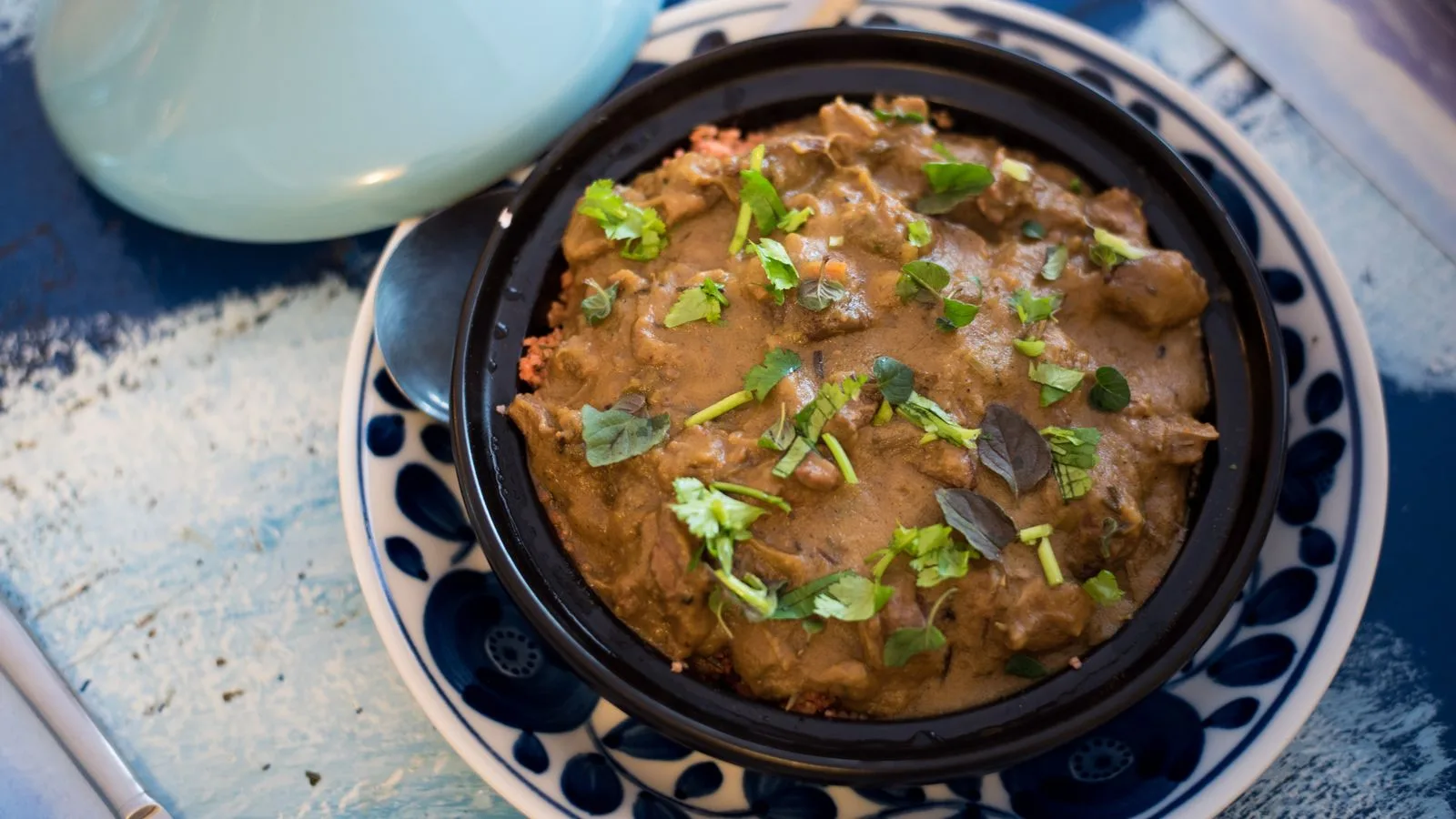 A savory Moroccan tagine garnished with fresh herbs, served in a traditional dish.