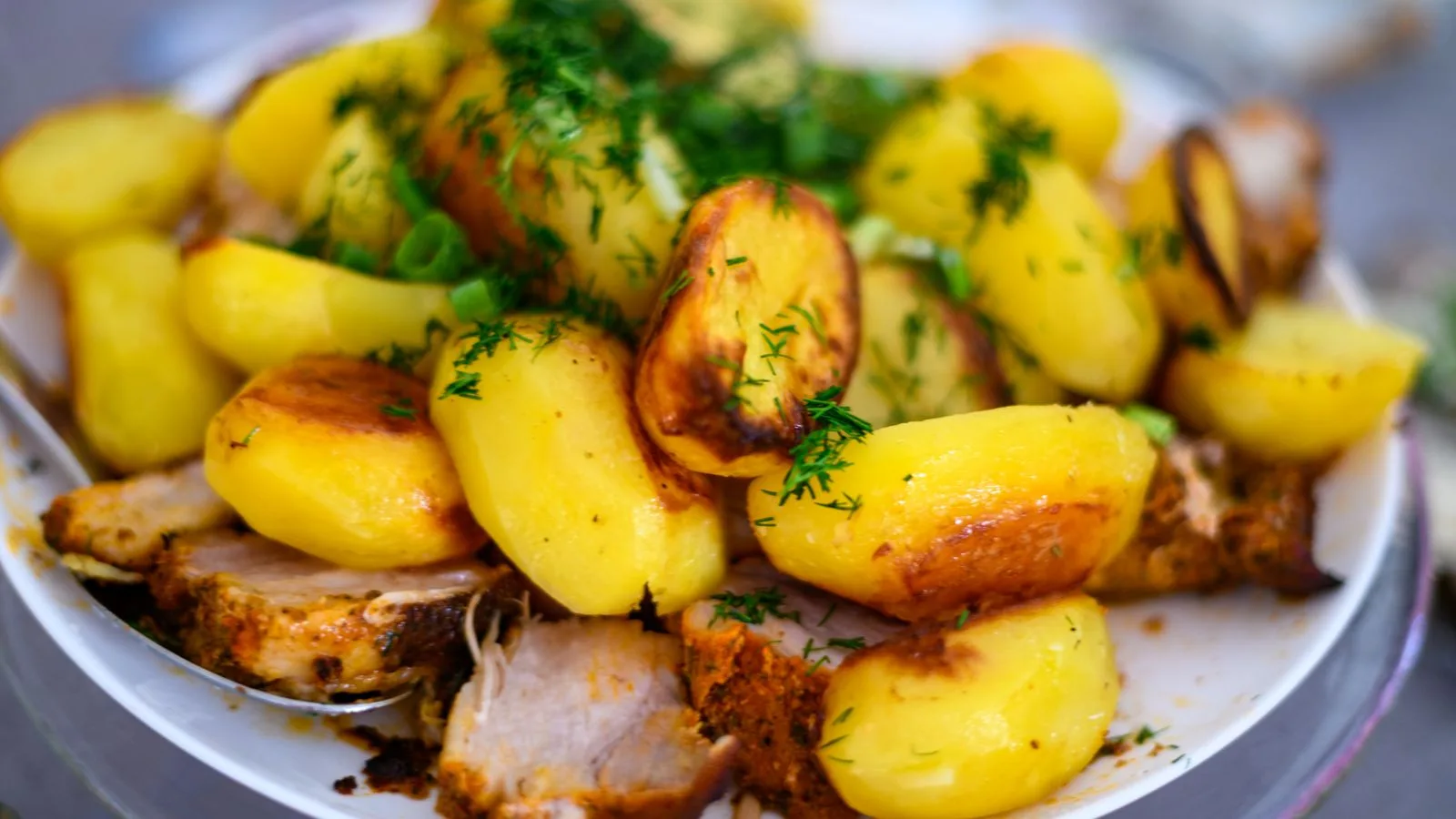 Delicious roasted potatoes and meat garnished with fresh dill, perfect for a hearty meal.