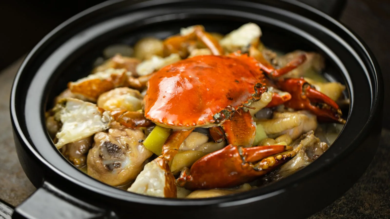 Tasty seafood stew with crab and mushrooms in a black pot, perfect for gourmet dining.