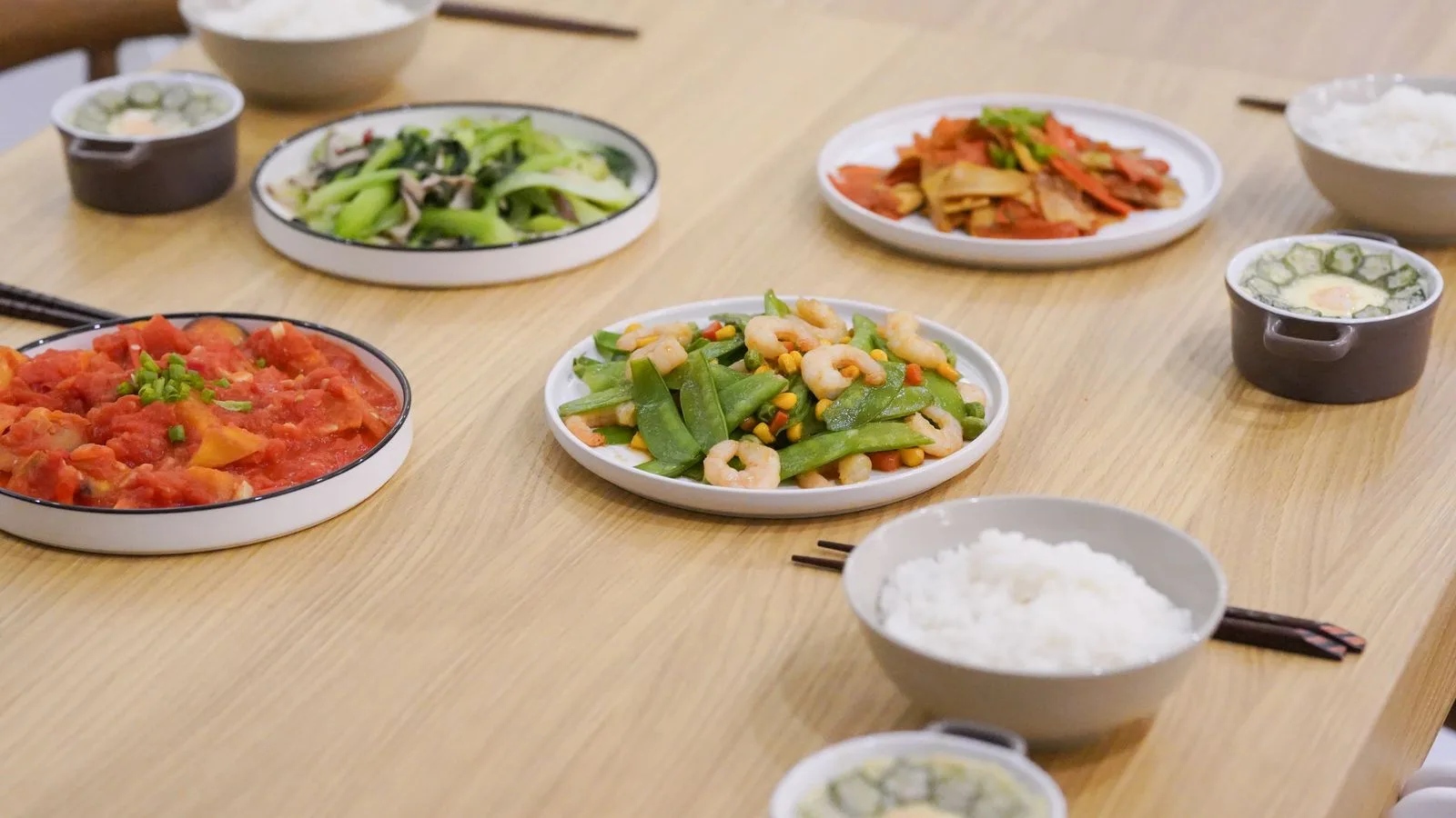 A variety of Asian dishes served on a wooden table, showcasing colorful and healthy ingredients.