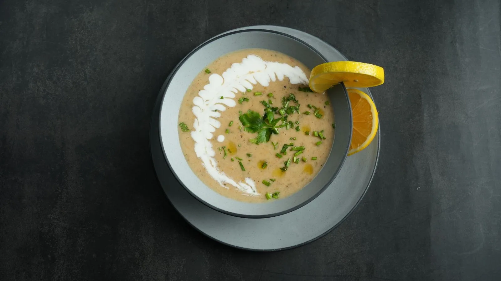 A delicious creamy soup garnished with fresh parsley and lemon slice.