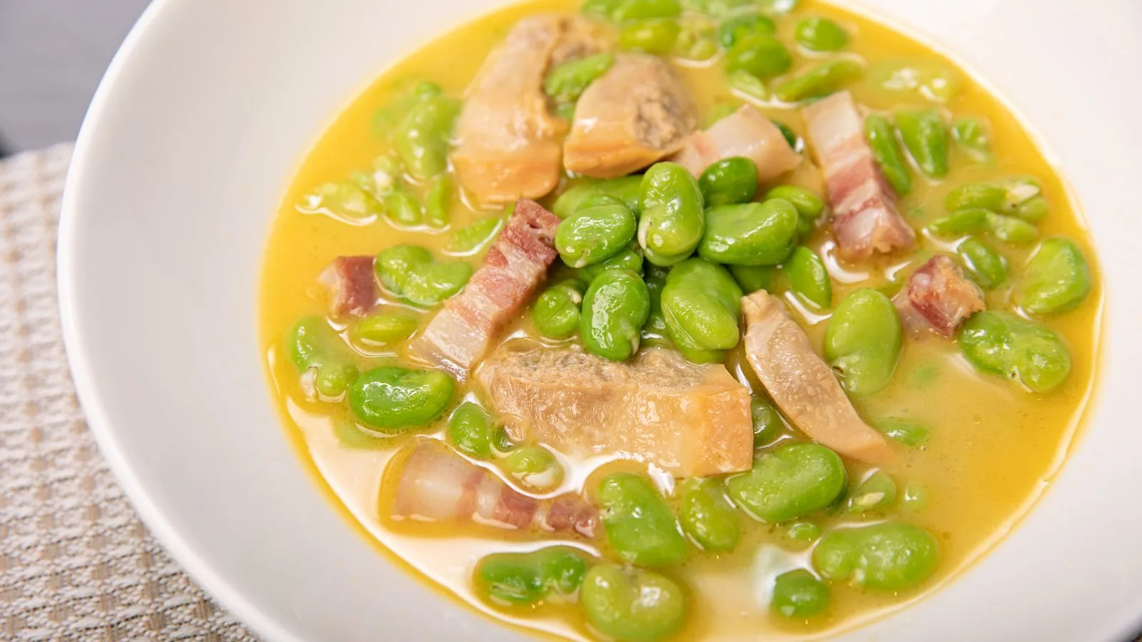 Hearty soup with broad beans and bacon in a rich broth, perfect for a comforting meal.