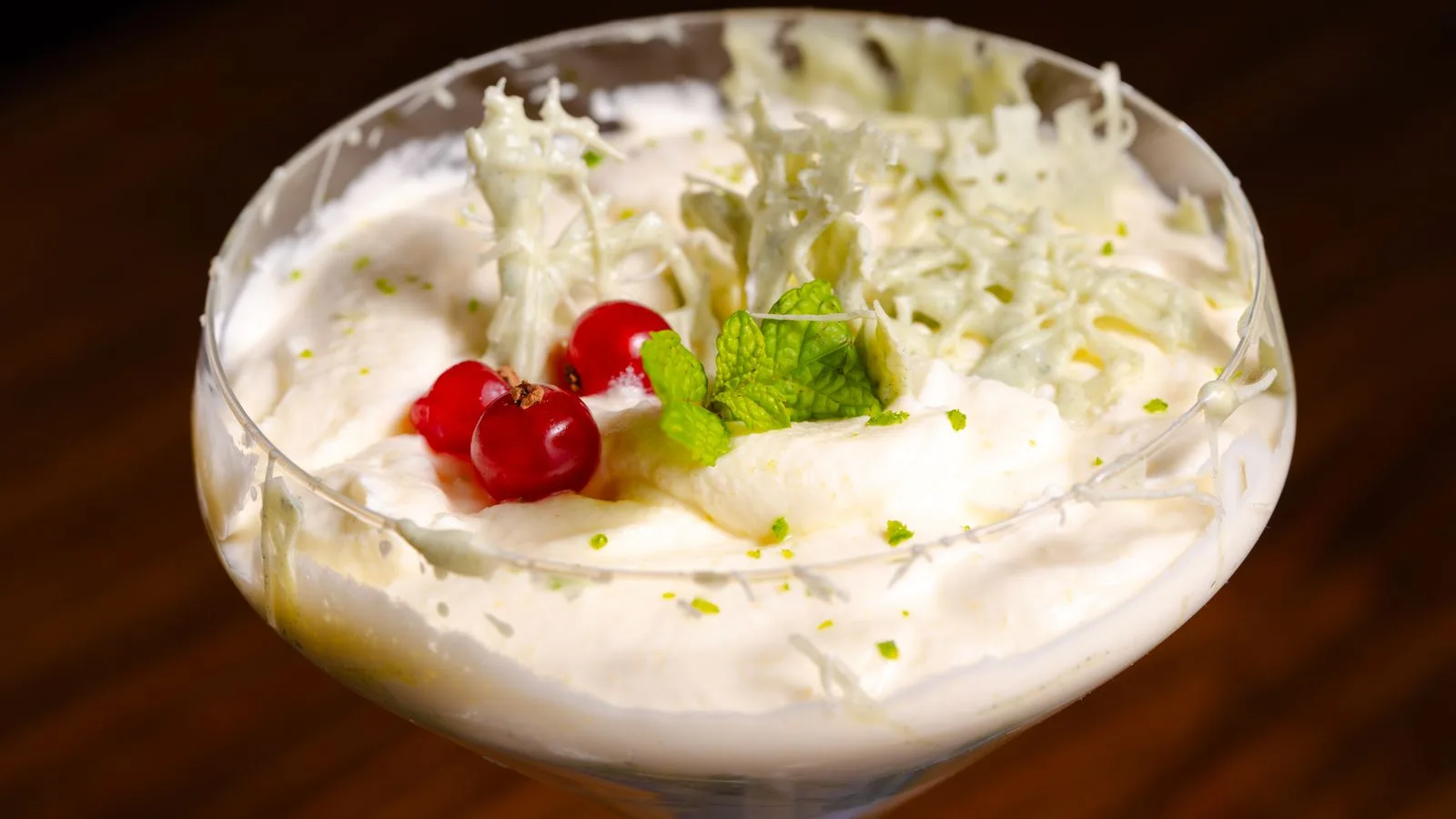 Close-up of a creamy dessert garnished with berries and mint, perfect for gourmet dining.