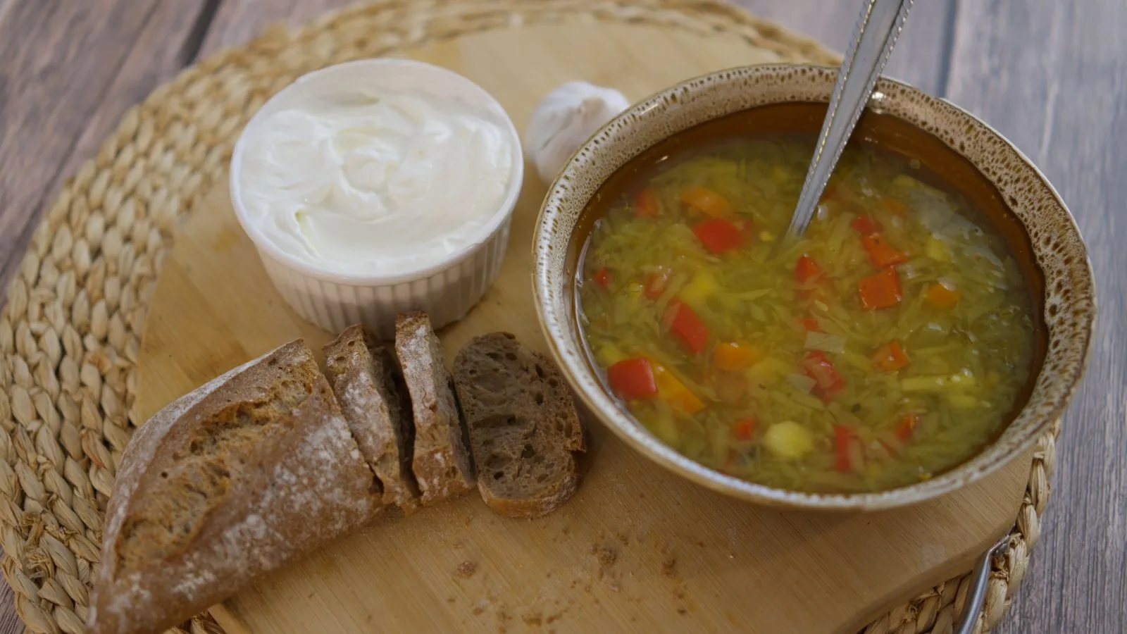 A cozy rustic lunch featuring vegetable soup with crusty bread and creamy spread.
