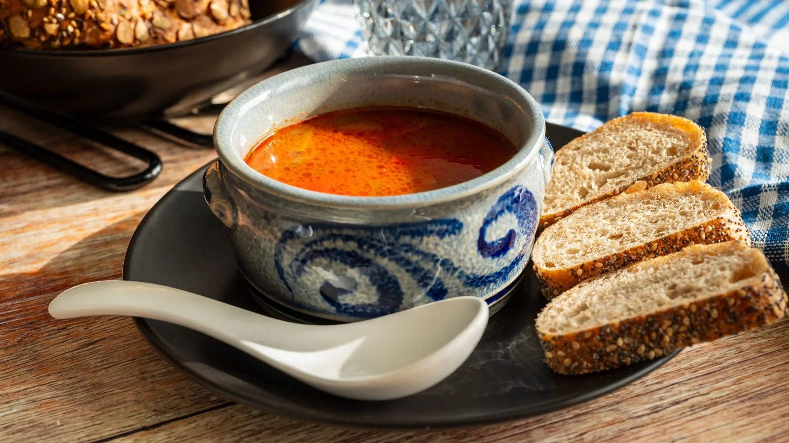 Hearty solyanka soup served with slices of rustic bread on a table.
