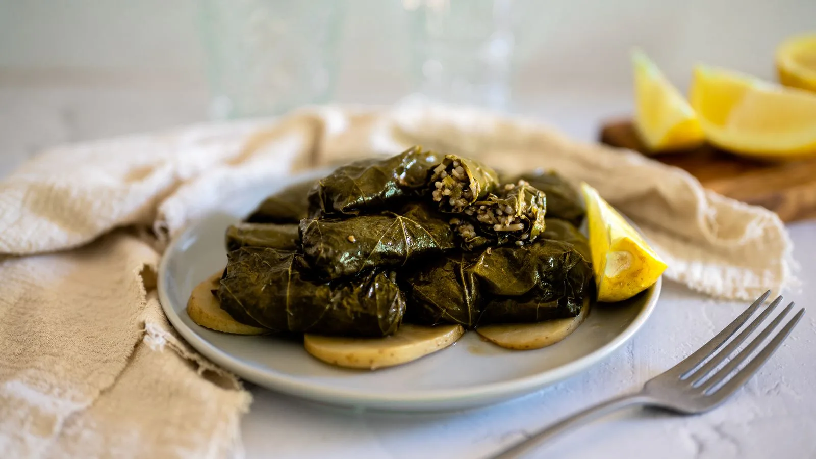 Close-up of stuffed grape leaves on a plate with lemon slices, perfect for a Mediterranean meal.