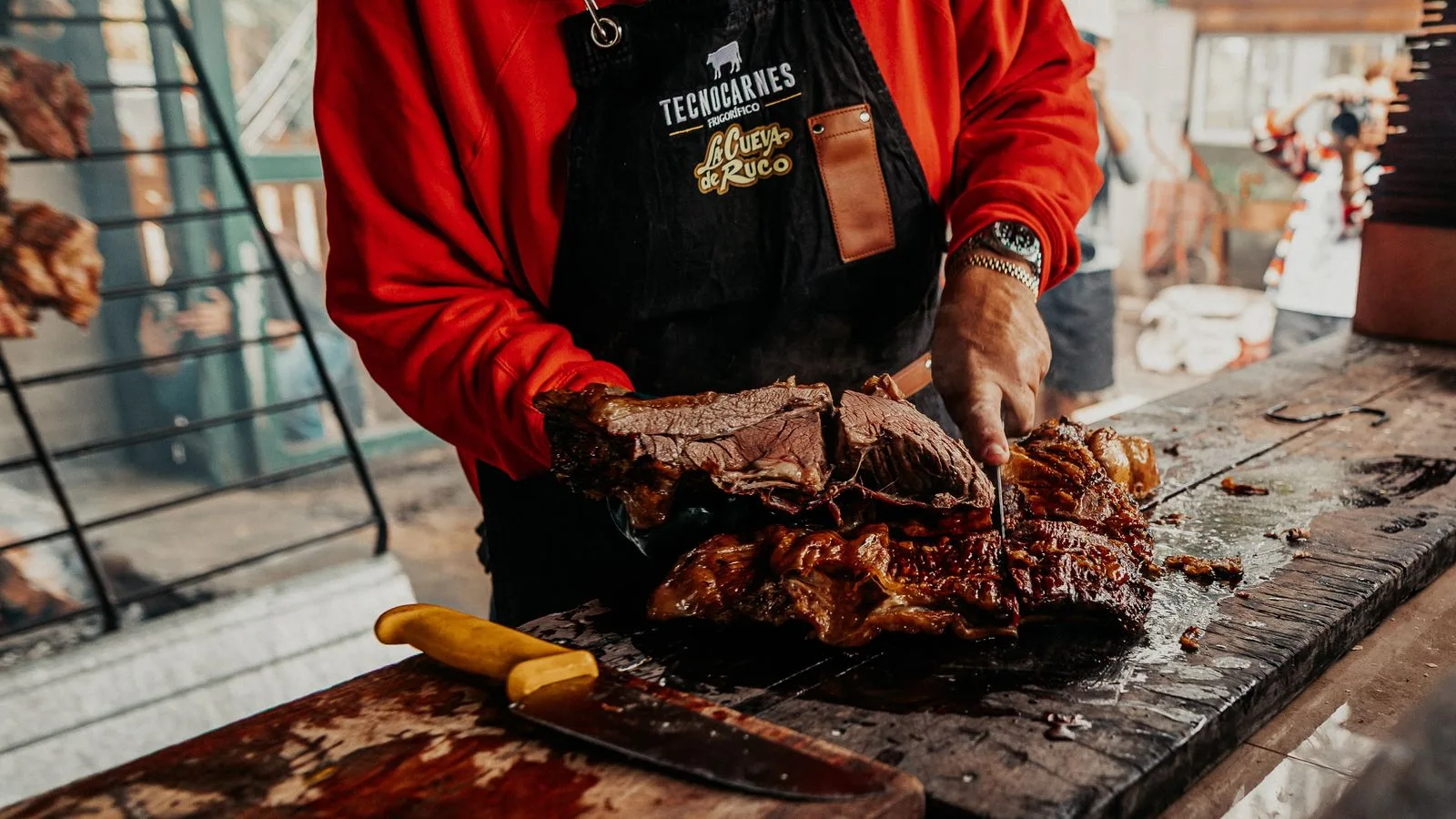 A cook preparing traditional Argentine asado with grilled beef slices in Provincia de Buenos Aires, Argentina.