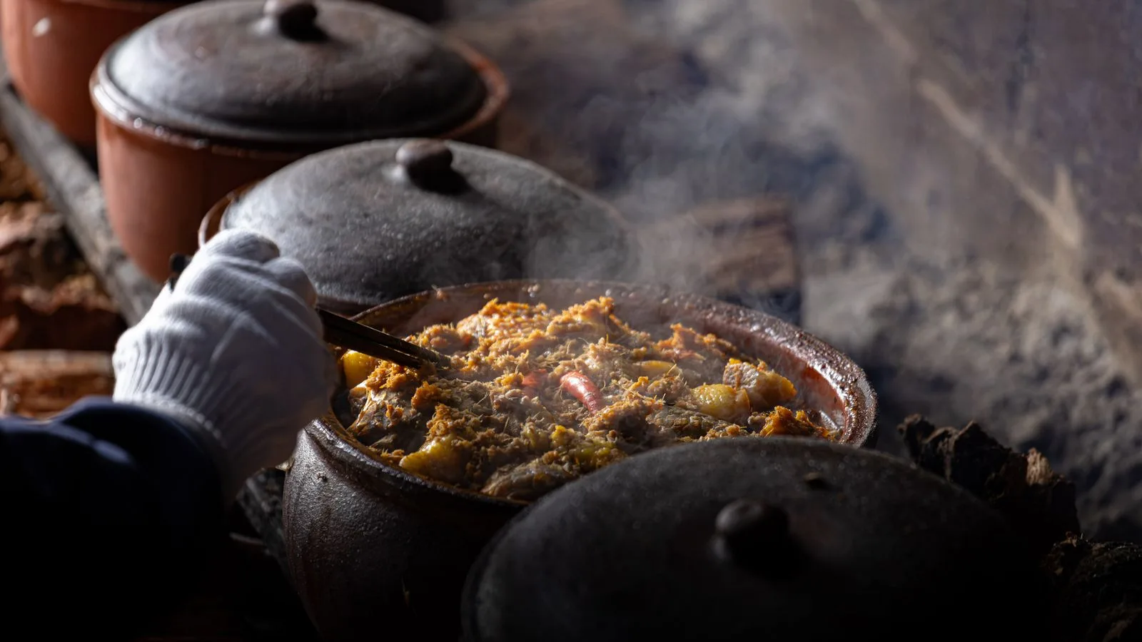 Steaming hot Vietnamese dish cooking in clay pots over rustic stove, adding authentic flavor.