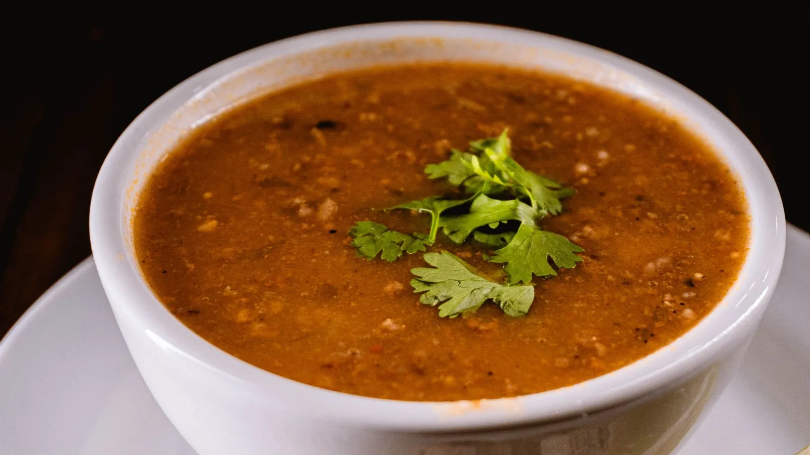 Warm bowl of lentil soup garnished with fresh cilantro leaves, perfect for cozy dining.