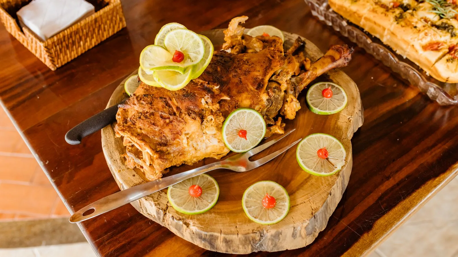 Delicious roasted lamb served with lime slices and garnishes on a wooden platter.