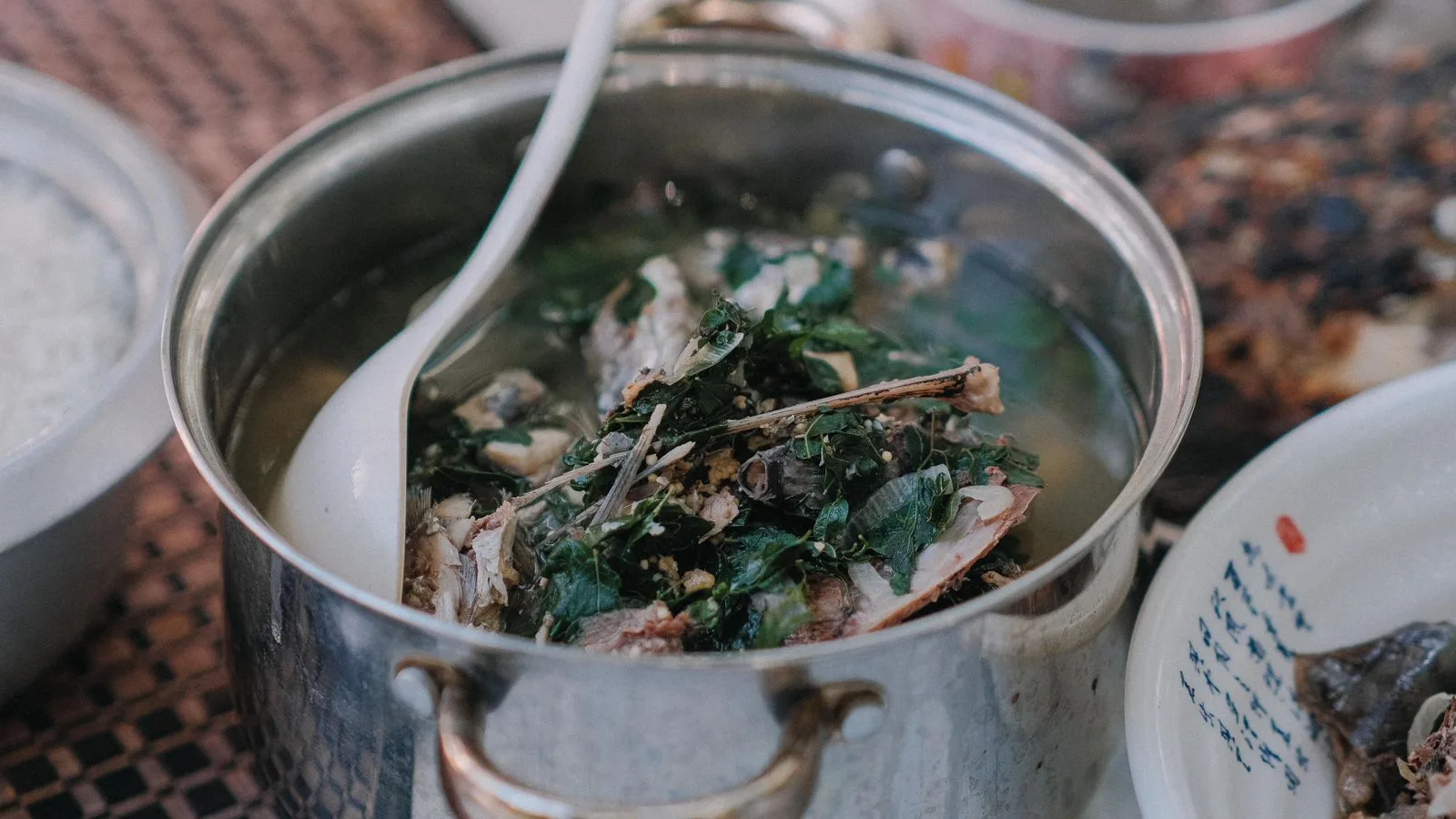Warm homemade fish soup with fresh herbs in a stainless steel pot, ready to serve.